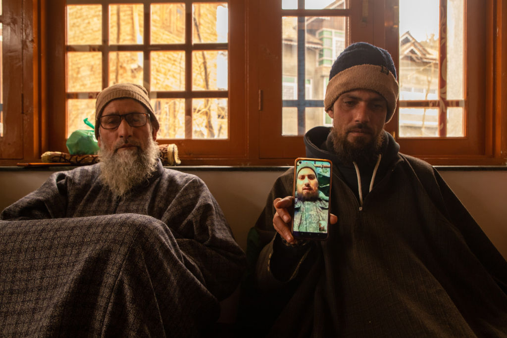 A brother holds a smart phone displaying the photos of Azad