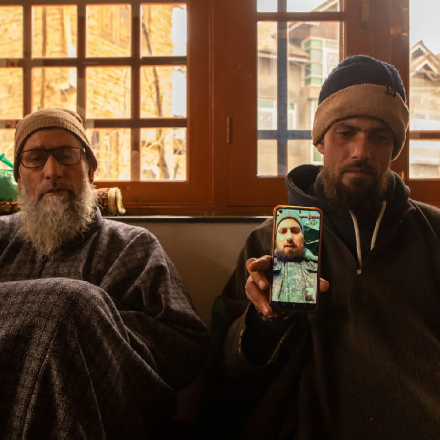 A brother holds a smart phone displaying the photos of Azad