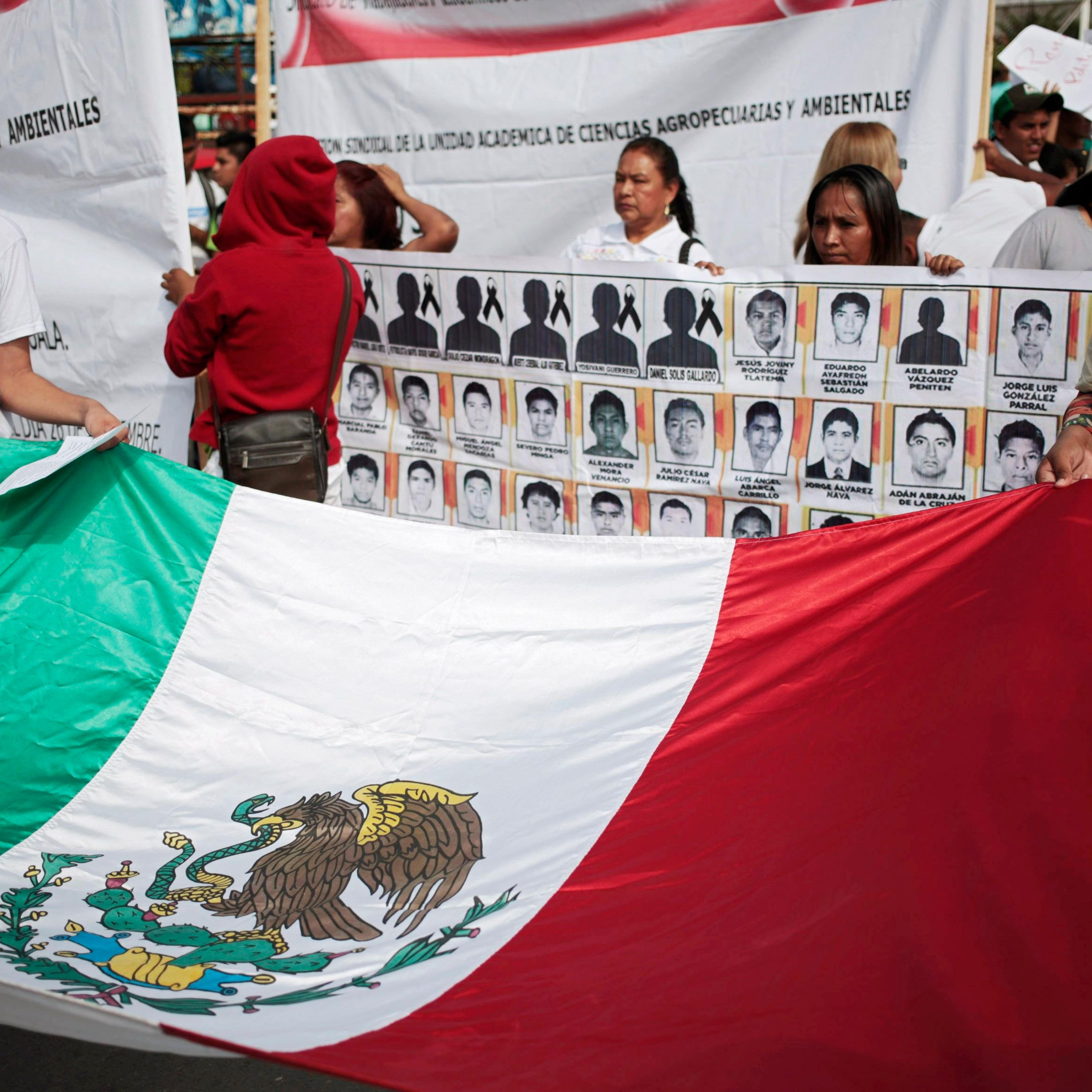 People hold a Mexican flag during a demonstration to demand information for the 43 missing students of the Ayotzinapa teachers' training college, in Iguala, the southern Mexican state of Guerrero on Oct. 22, 2014.