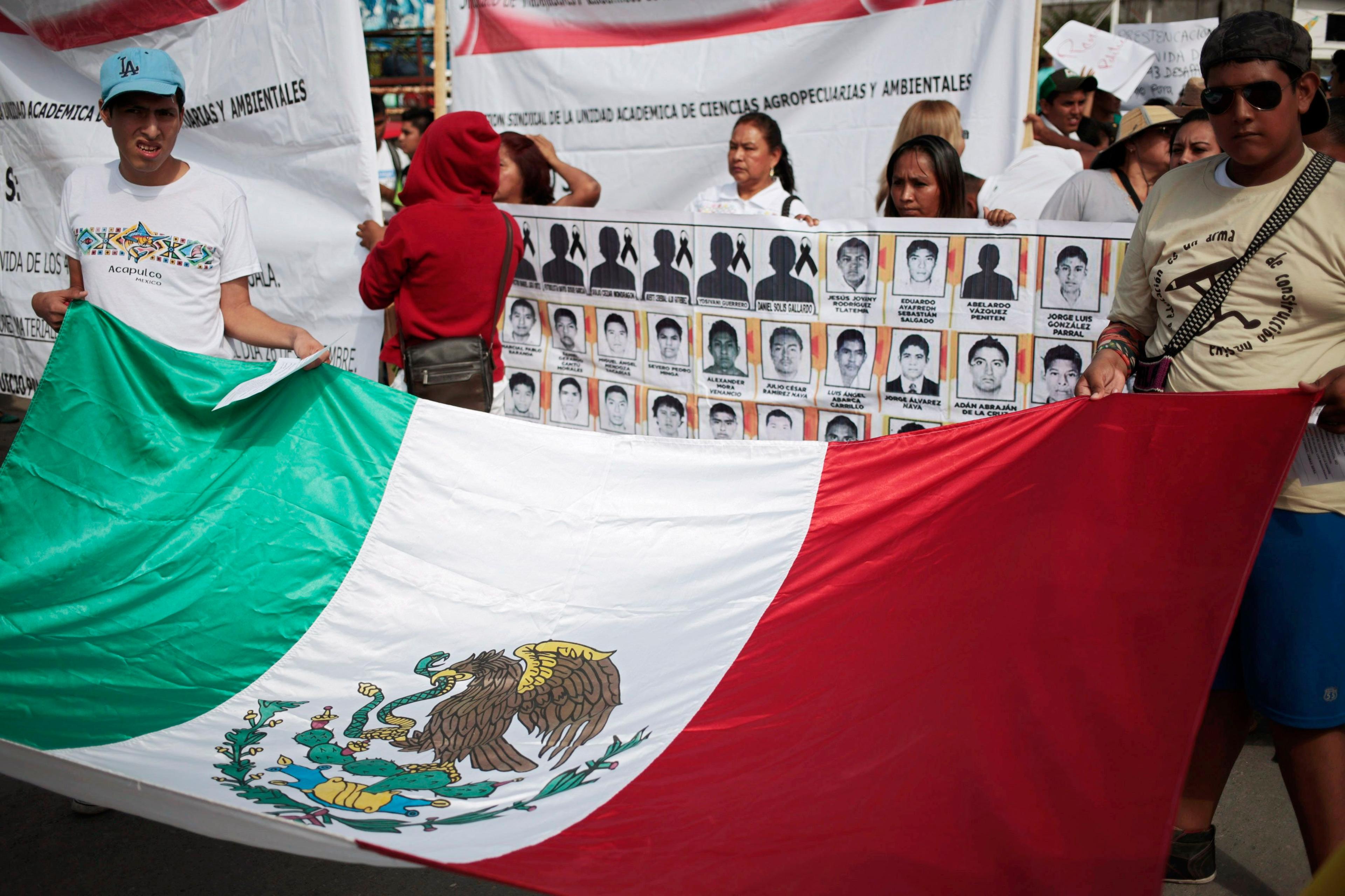 People hold a Mexican flag during a demonstration to demand information for the 43 missing students of the Ayotzinapa teachers' training college, in Iguala, the southern Mexican state of Guerrero on Oct. 22, 2014.