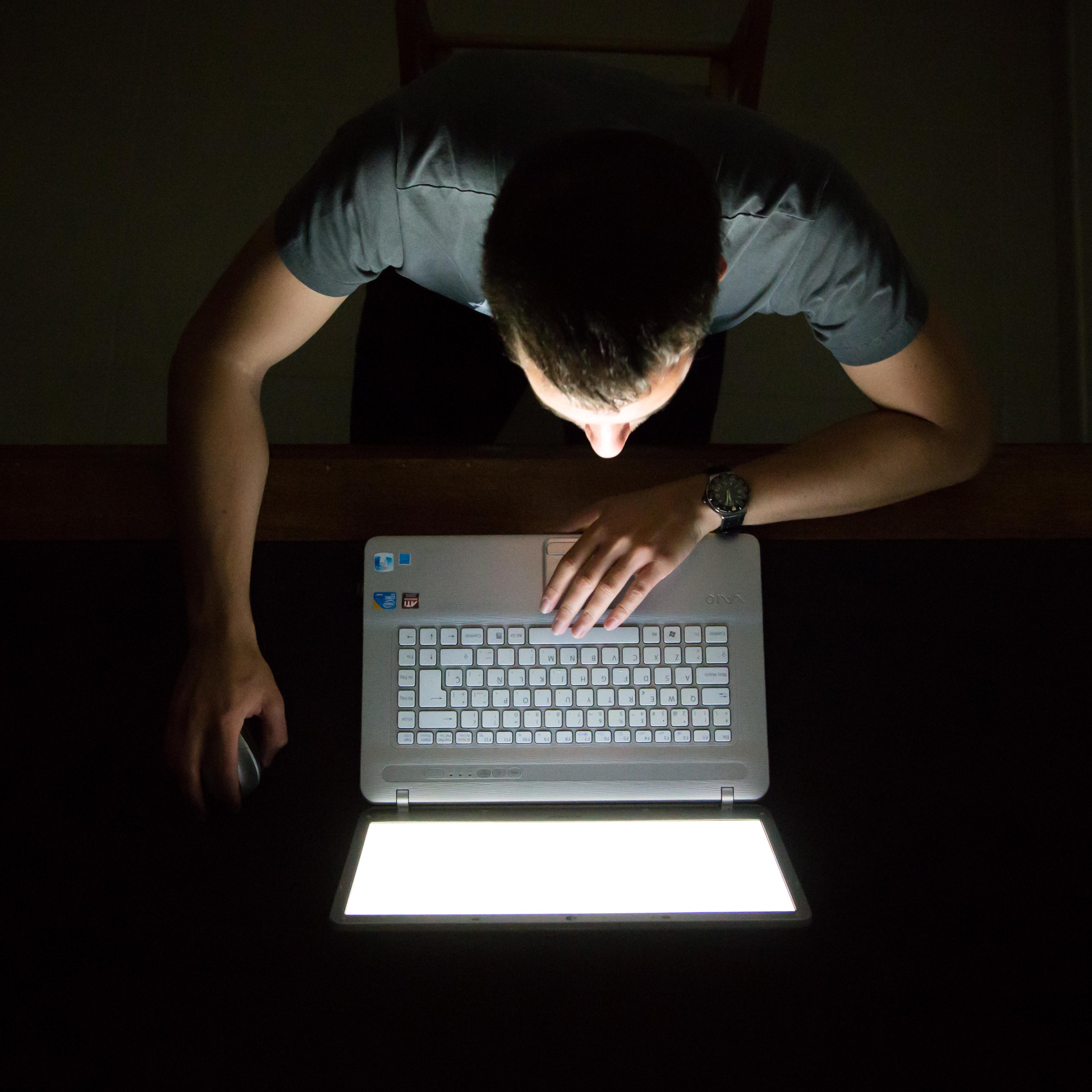 Guy checking internet with laptop at late night with dark room, view from above.