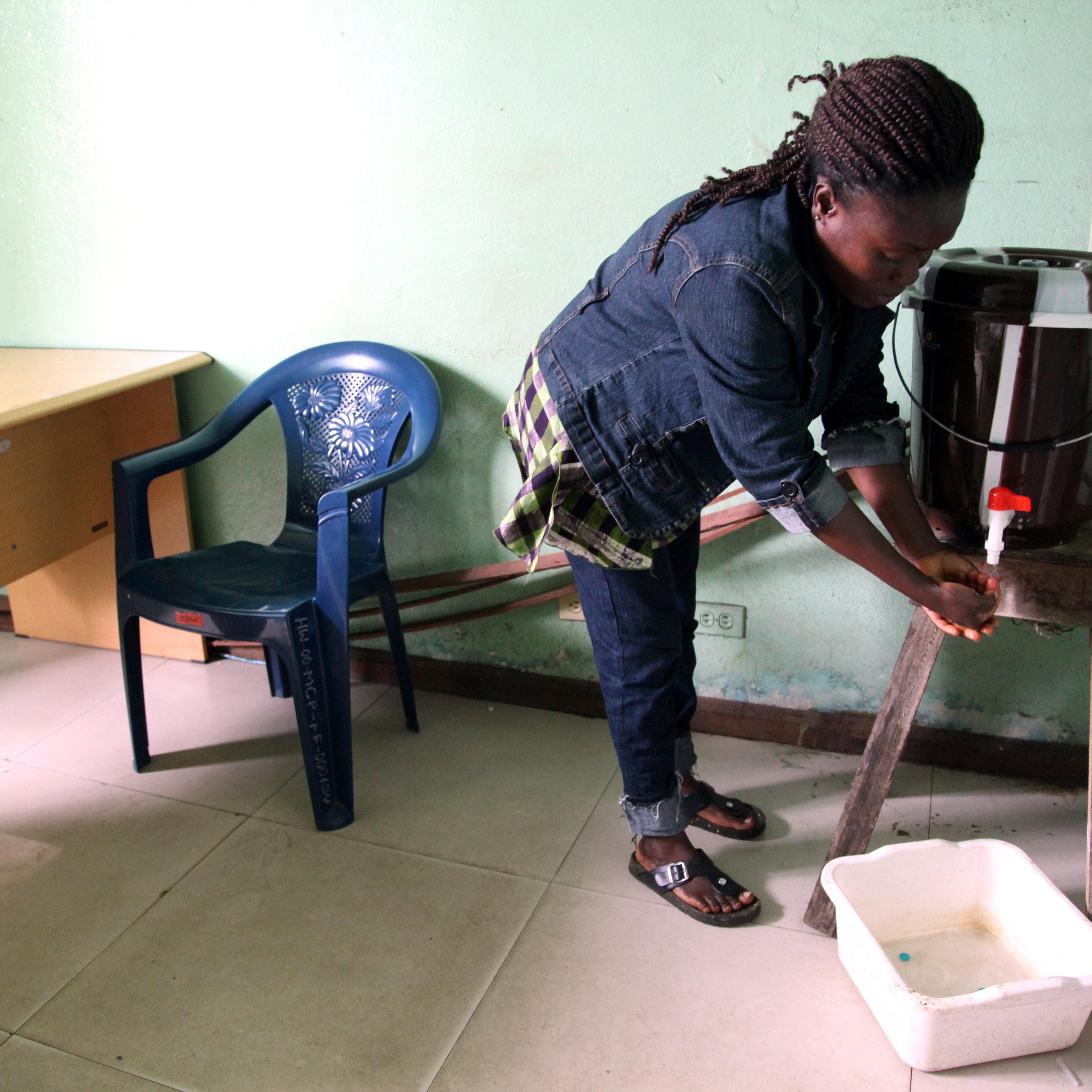 Washing hands with chlorine water, as this woman does at a public health center on July 31 in Monrovia, Liberia, is among the few ways to protect against Ebola, since there are no vaccines or treatments against infection