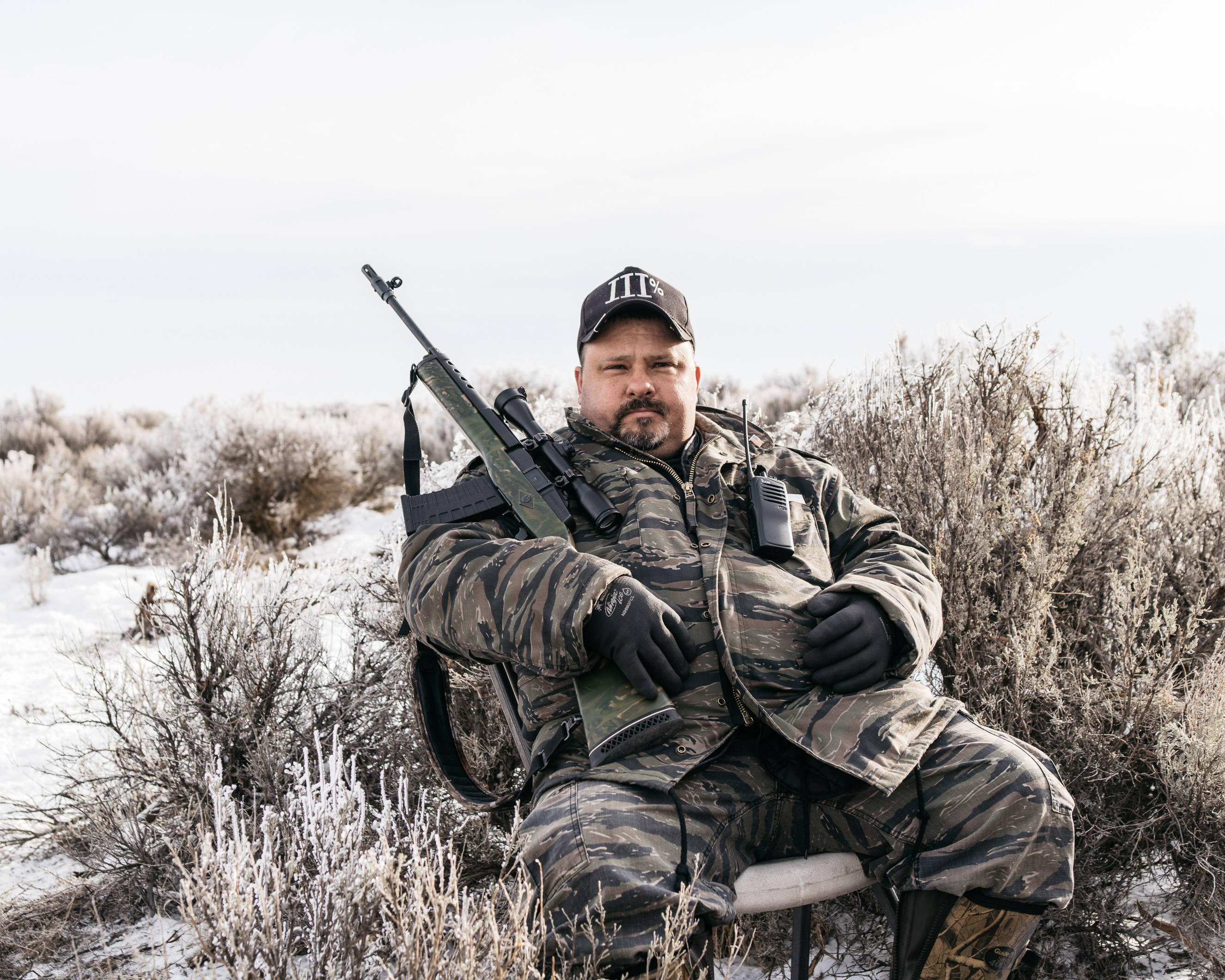 An armed member of the activist group 3% of Idaho sits near the blockaded entrance to the Malheur National Wildlife Refuge on Jan. 12, 2016.