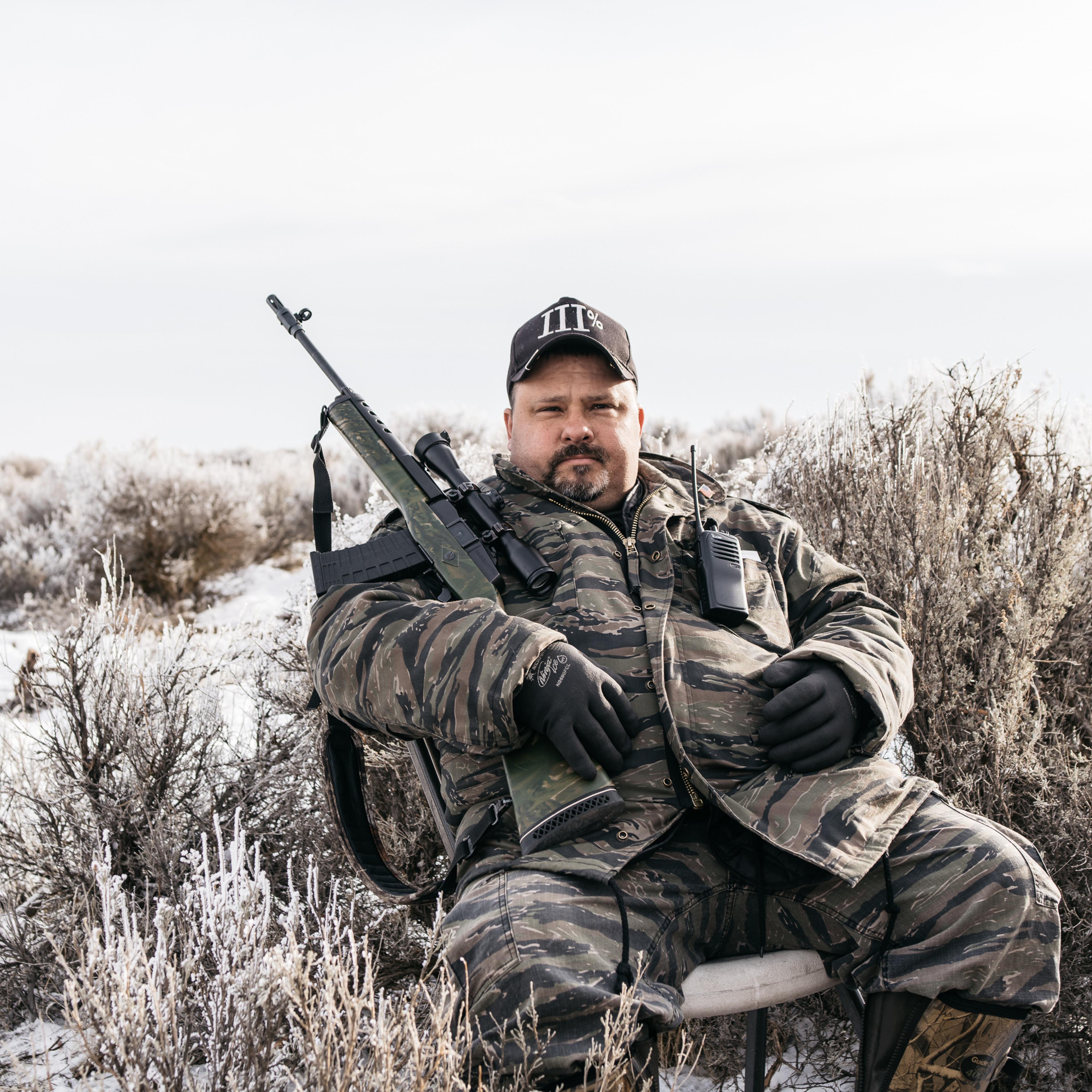 An armed member of the activist group 3% of Idaho sits near the blockaded entrance to the Malheur National Wildlife Refuge on Jan. 12, 2016.
