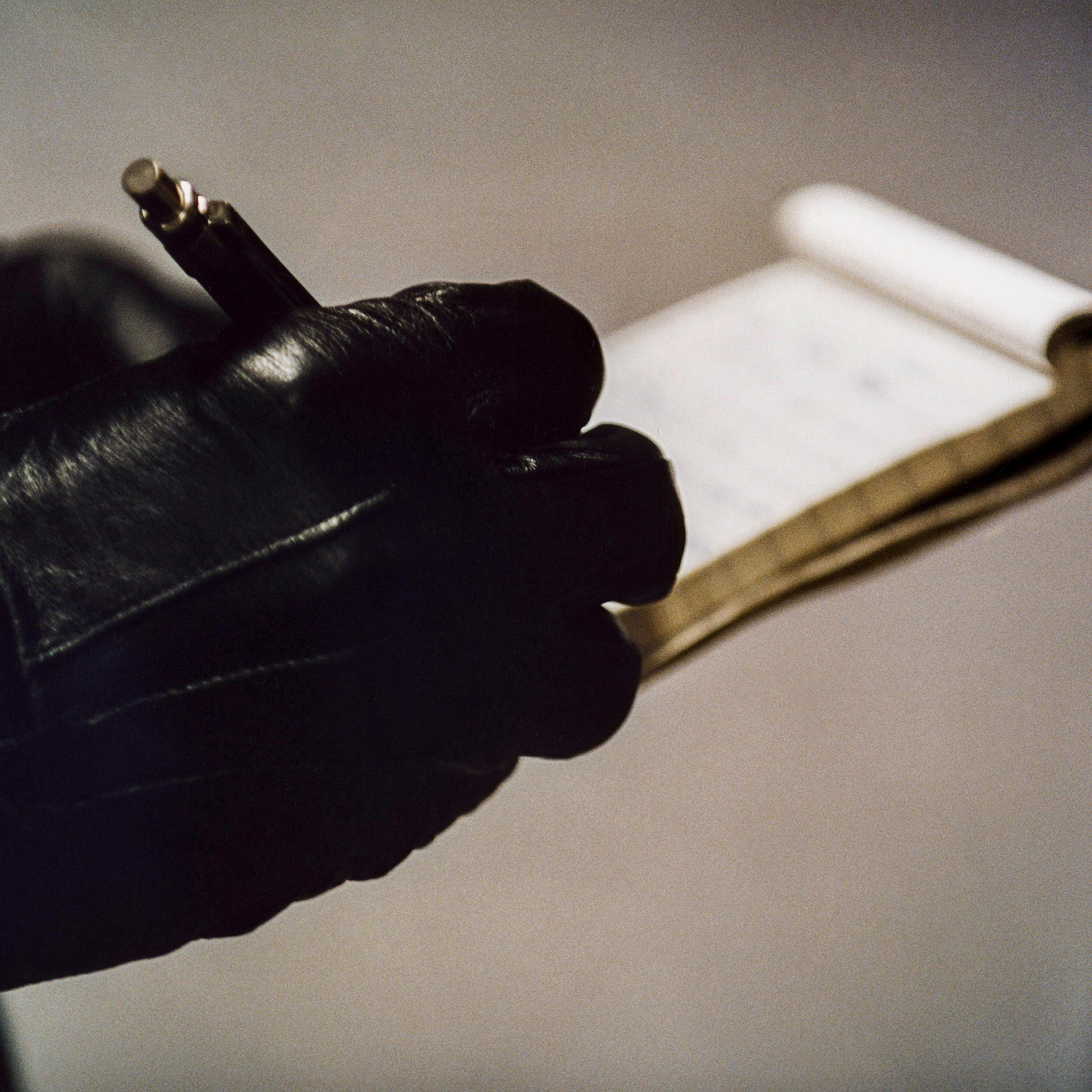 A police officer's hand in gloves write on a notepad.