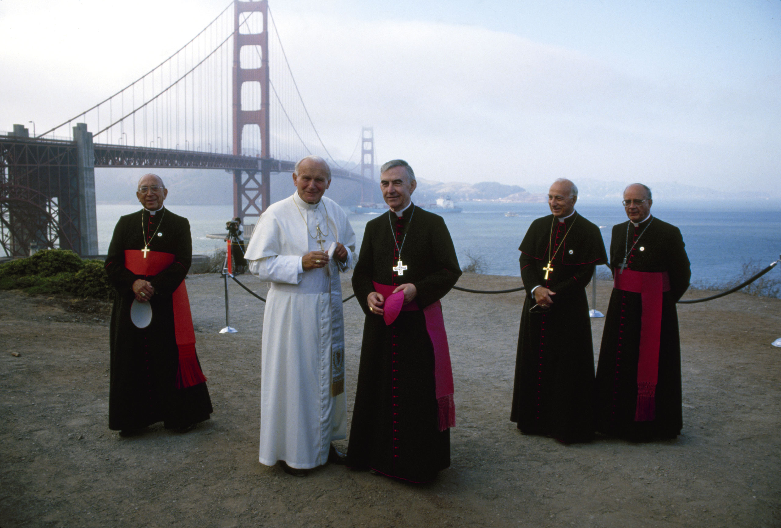 Pope John Paul II (born poses with American Bishop (and later Archibishop) John R. Quinn (center) during a visit to Golden Gate Park, San Francisco, California, September 18, 1987. With them in the background are Italian Cardinal Secretary of State Agost