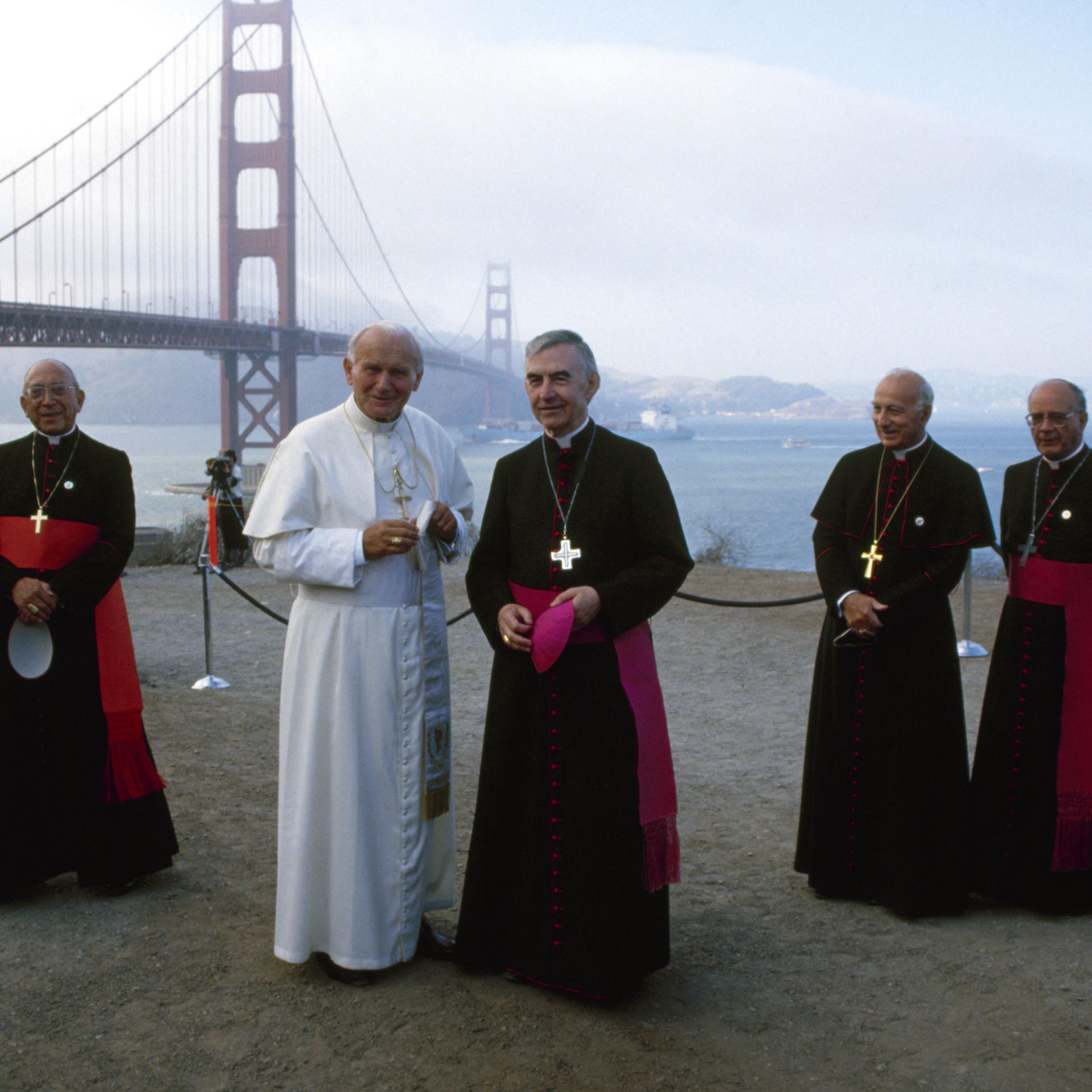 Pope John Paul II (born poses with American Bishop (and later Archibishop) John R. Quinn (center) during a visit to Golden Gate Park, San Francisco, California, September 18, 1987. With them in the background are Italian Cardinal Secretary of State Agost