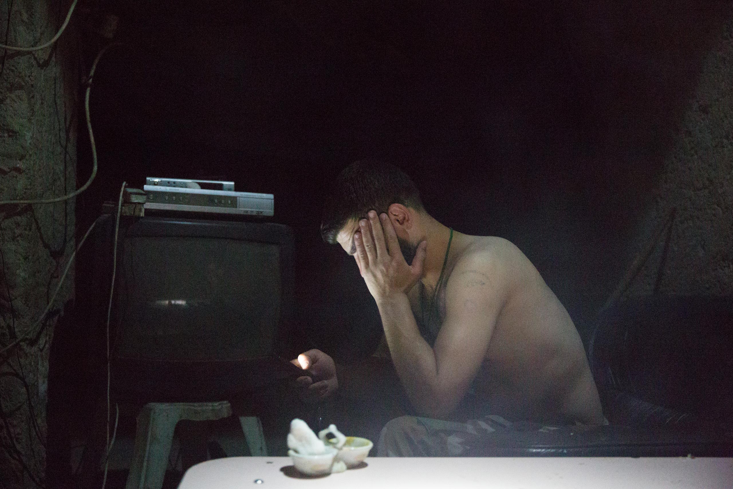 A Syrian government soldier checks his cell phone from a frontline position in Deir-ez Zor. For soldiers who have been at war for more than three years, their phones are a crucial way to maintain contact with loved ones, May 28, 2015.