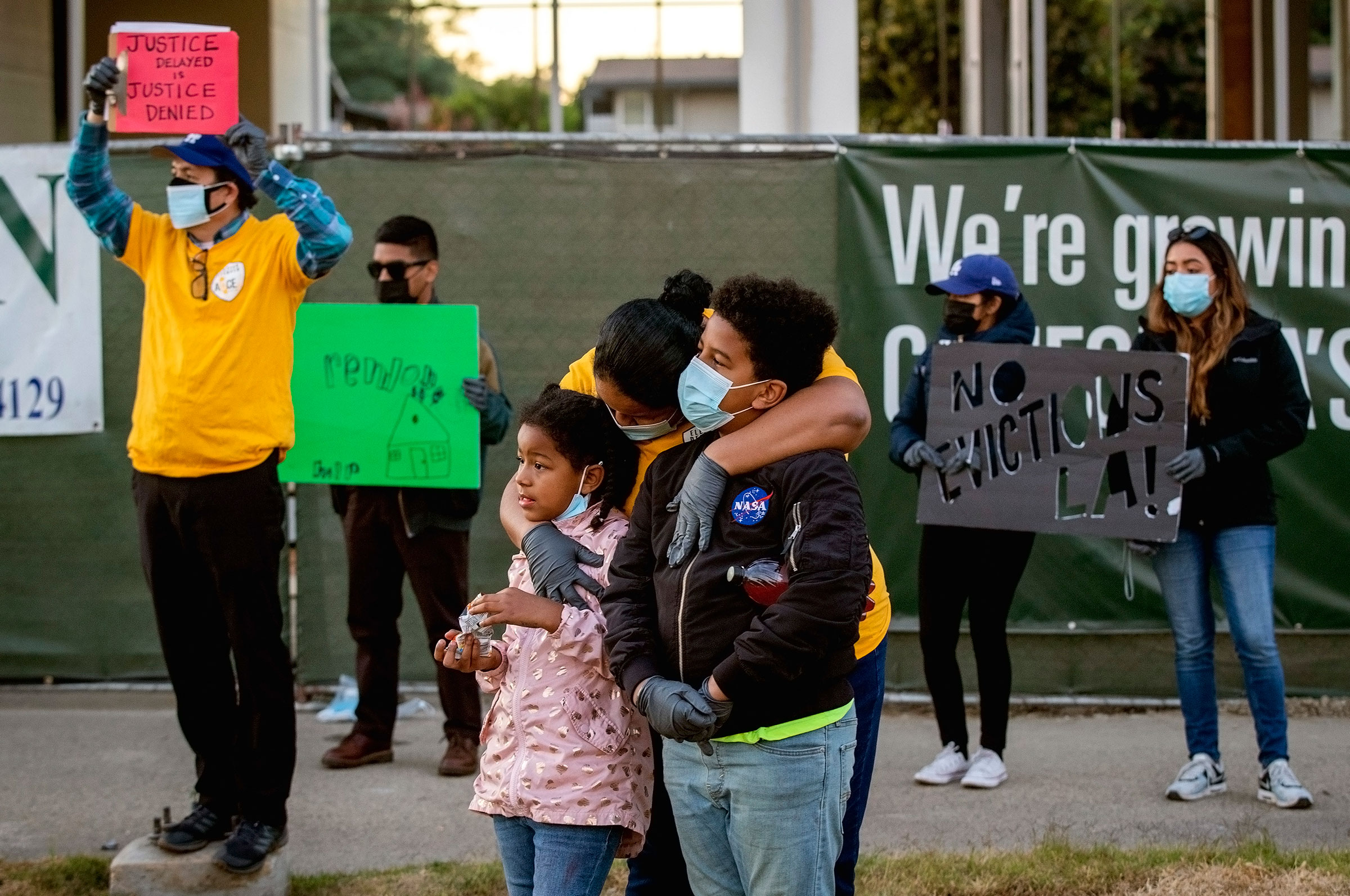 Kennia Viera, of Los Angeles, center, who is a single mom, unemployed and in danger of being evicted at the end of January, hugs her kids, Florisabella Houston-Viera, 7, and Enrique Houston-Viera, 9, after speaking at a protest for tenants in danger of e