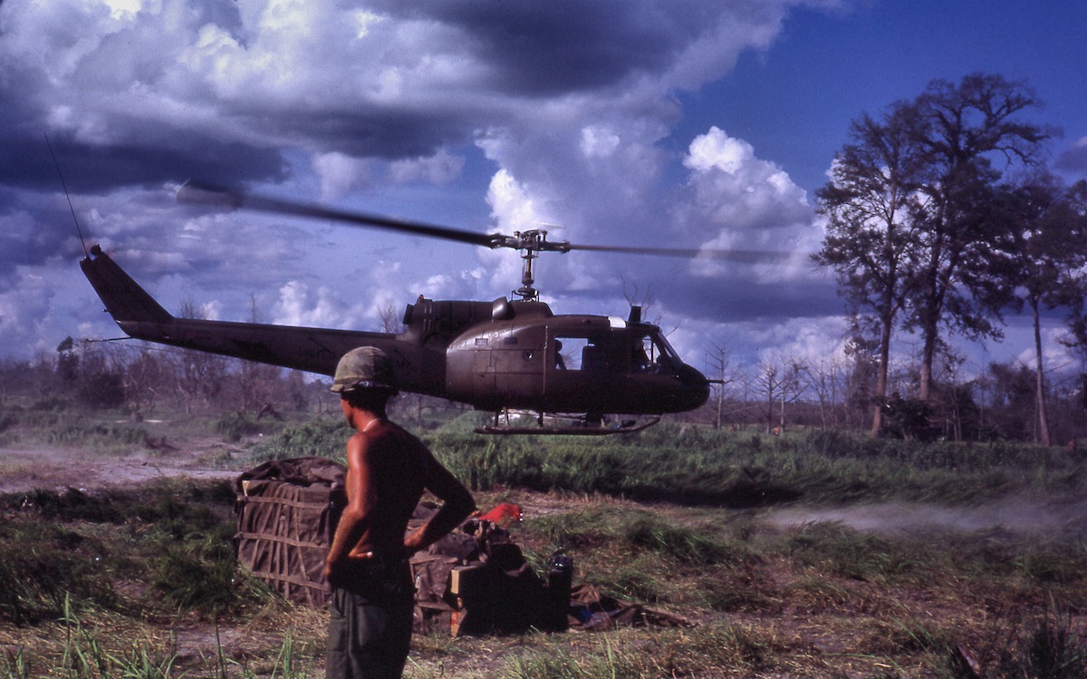 LZ, 1967: "Bell UH-1 Iroquois (Huey “Slick”) helicopter makes a quick troop drop at a Fire Support Base near the Cambodian border without touching down." 