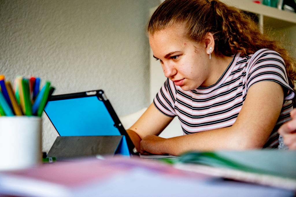 A female student uses her digital tablet to study at home.