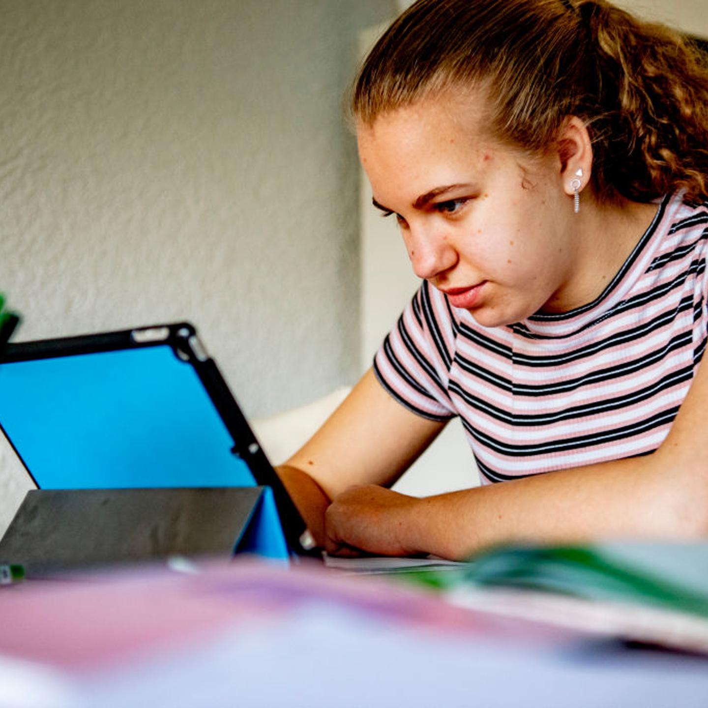 A female student uses her digital tablet to study at home.