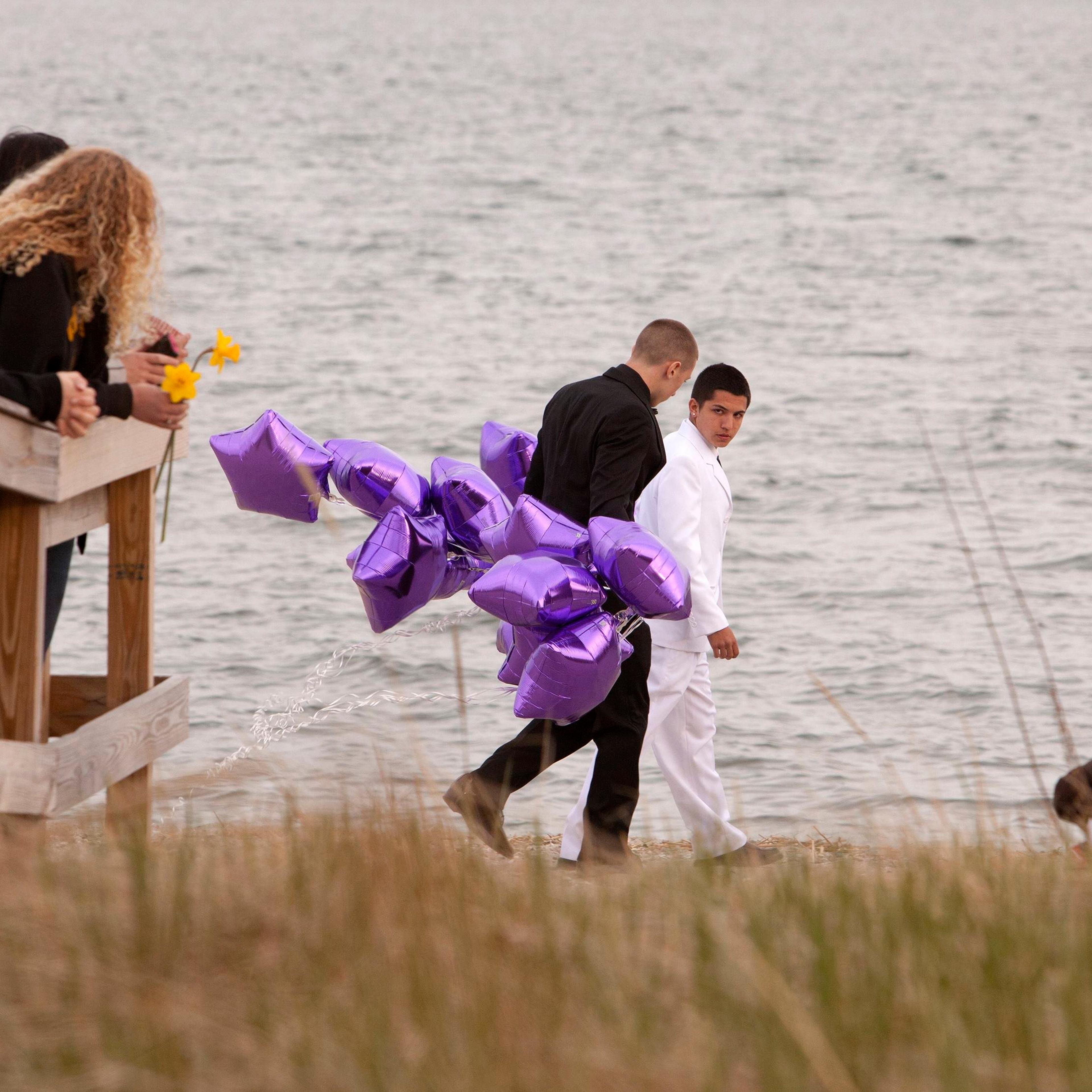 Students arrive at beach for vigil in honor of slain student Sanchez wearing prom clothes carrying balloons in Milford