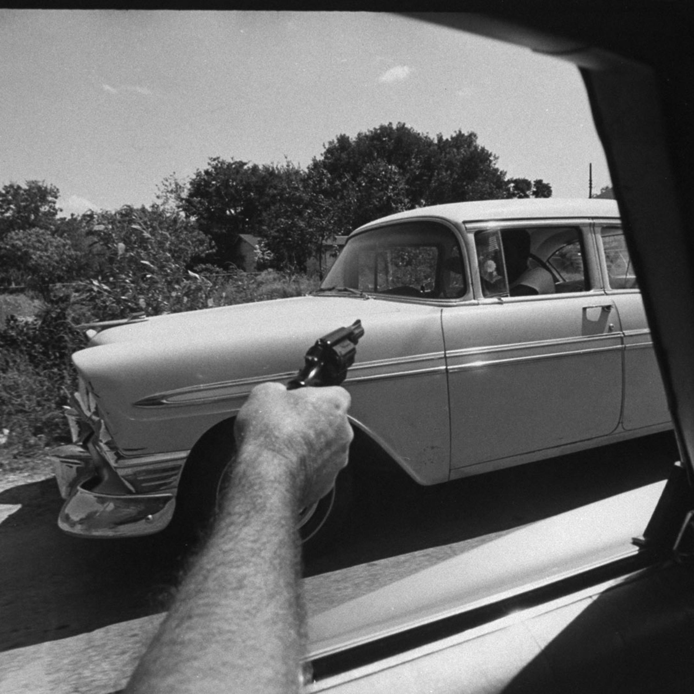 A U.S. Customs agent points his gun at a car suspected of transporting marijuana, 1969.