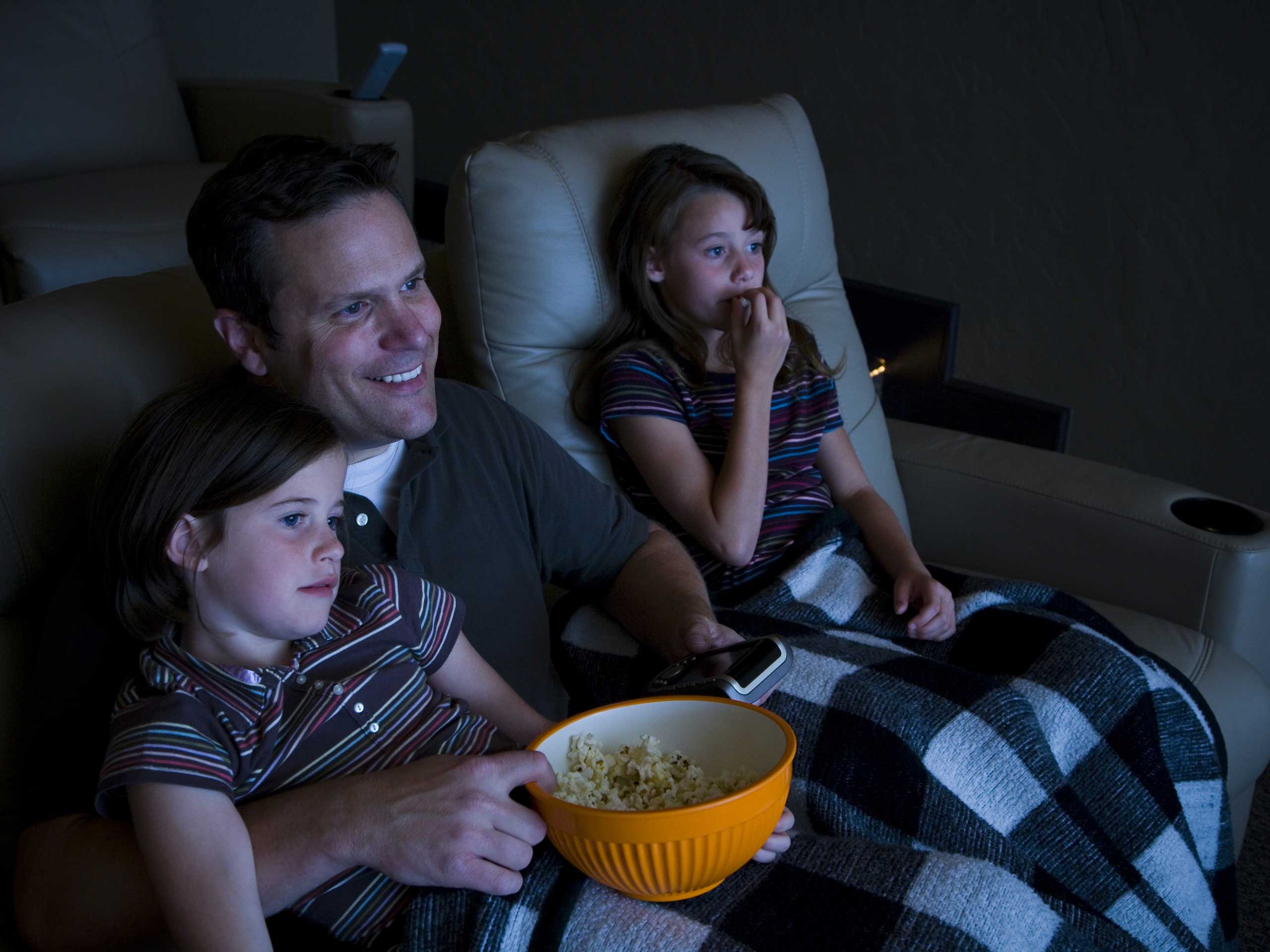 Father and daughters watching movie in home theater