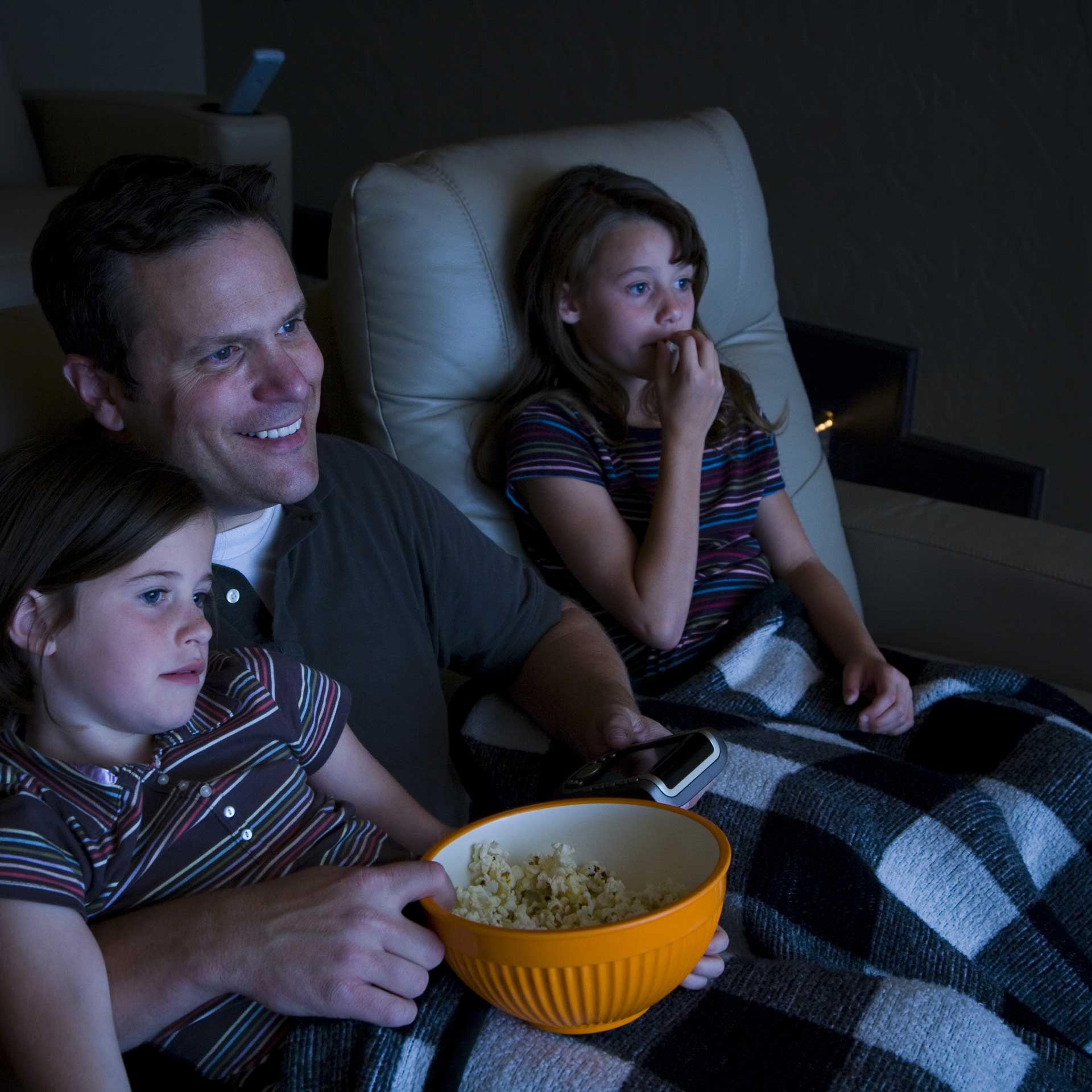 Father and daughters watching movie in home theater