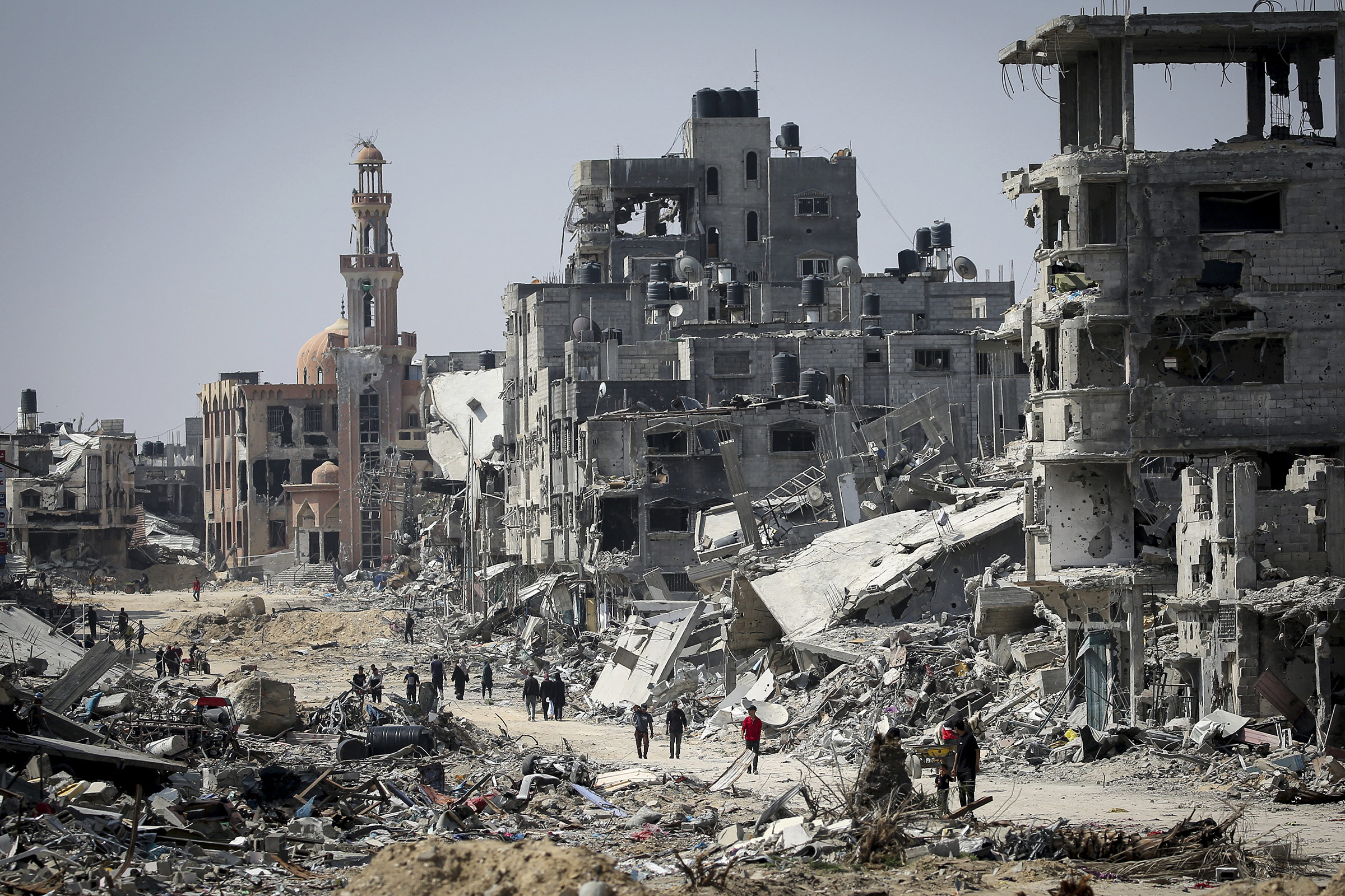 People walk amid the rubble of buildings destroyed during Israeli bombardment in Khan Yunis, Gaza, on April 16, 2024.