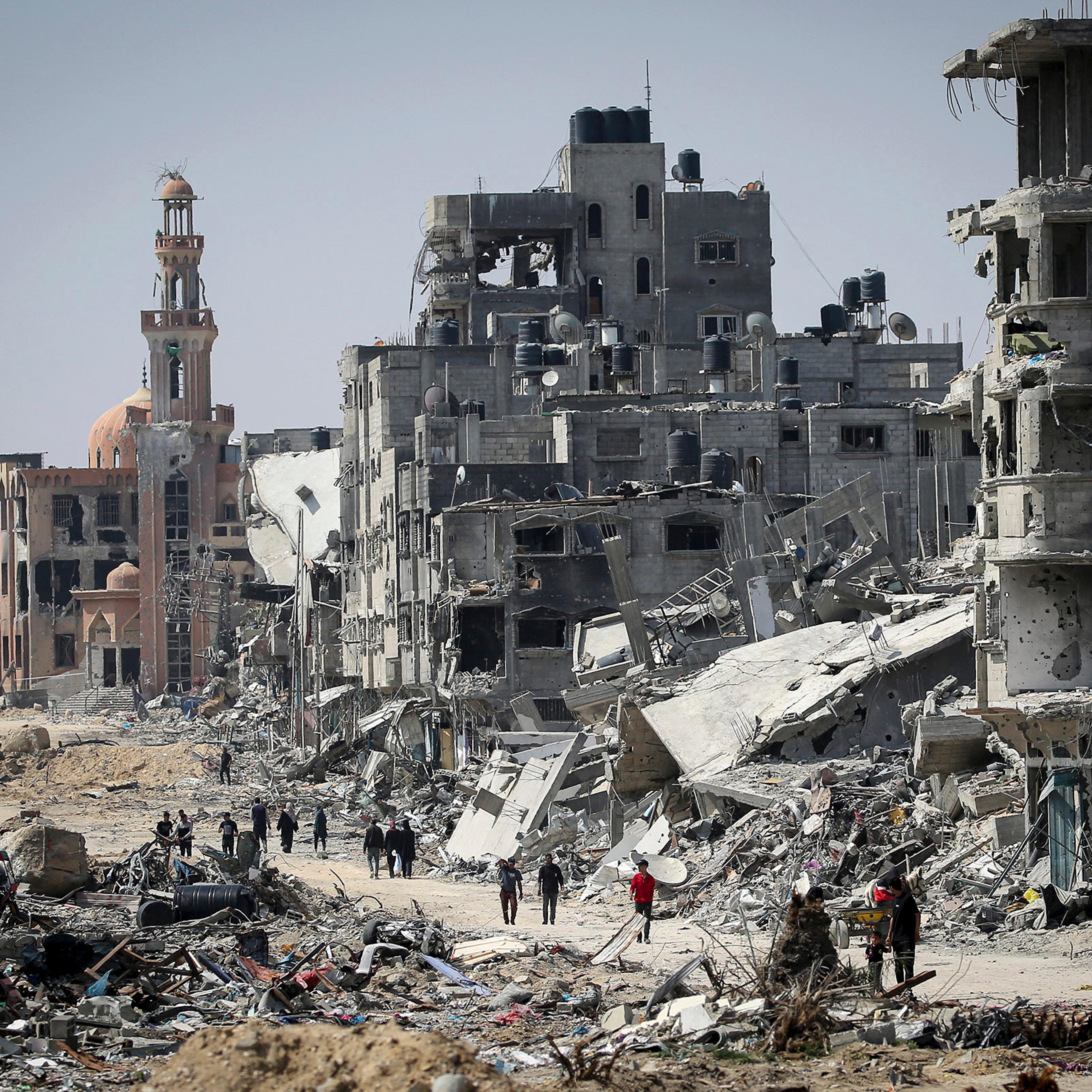 People walk amid the rubble of buildings destroyed during Israeli bombardment in Khan Yunis, Gaza, on April 16, 2024.