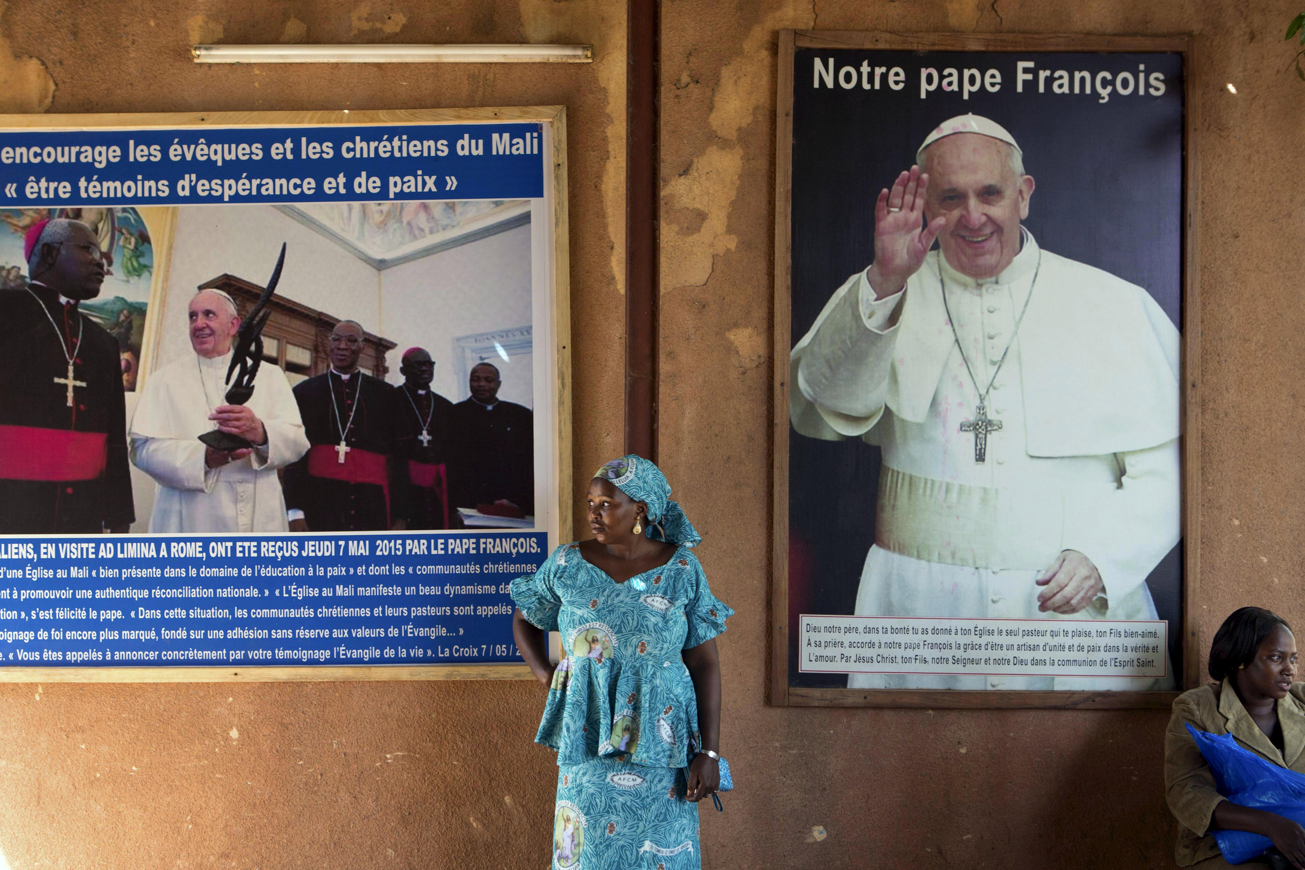 A woman stands in front of posters of Pope Francis at the Martyrs of Uganda church in Bamako, Mali, November 8, 2015. The poster on the right reads, "Our Pope Francis". Pope Francis makes his first pontifical visit later this month to Africa, where Catho