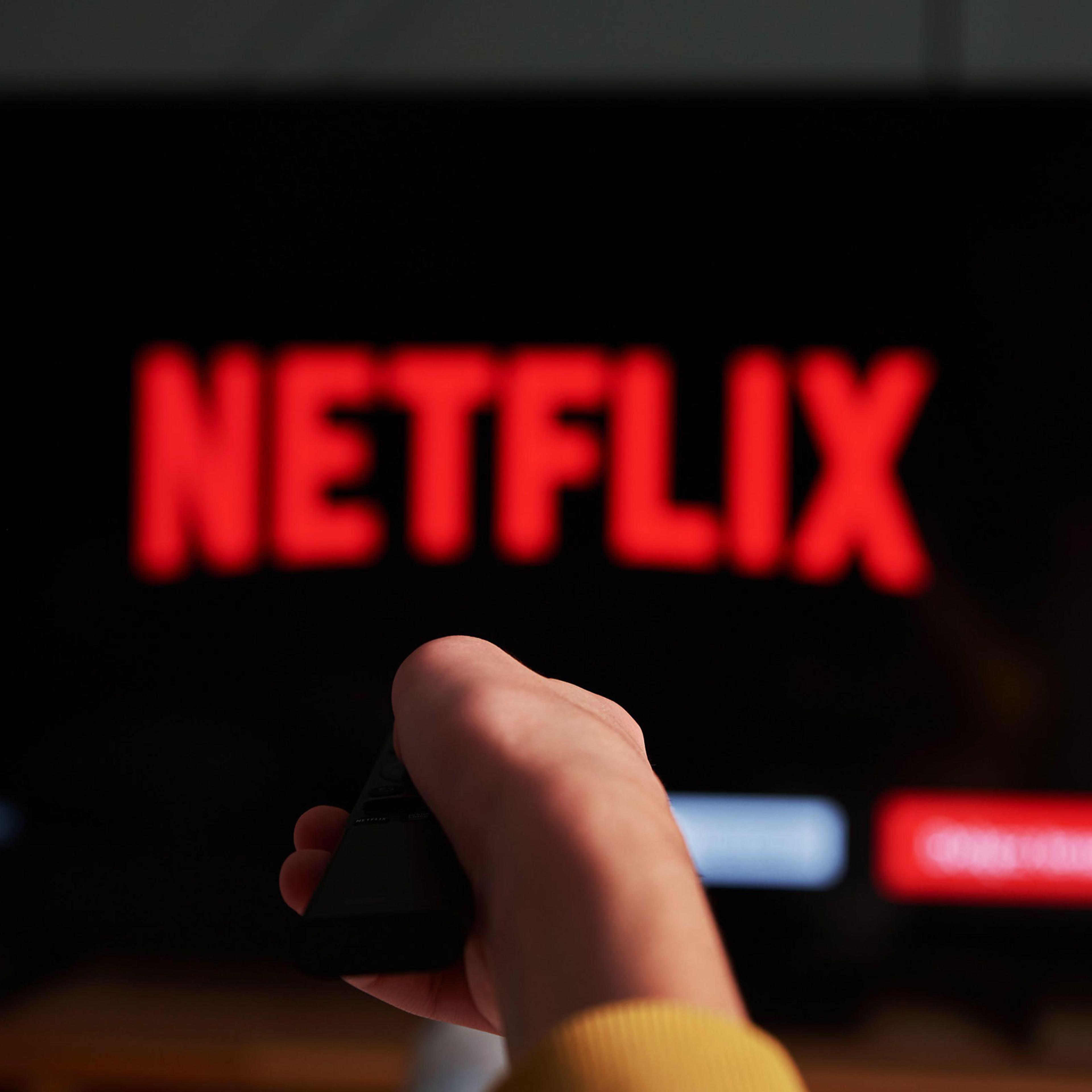 remote control in hand and TV set with Netflix logo