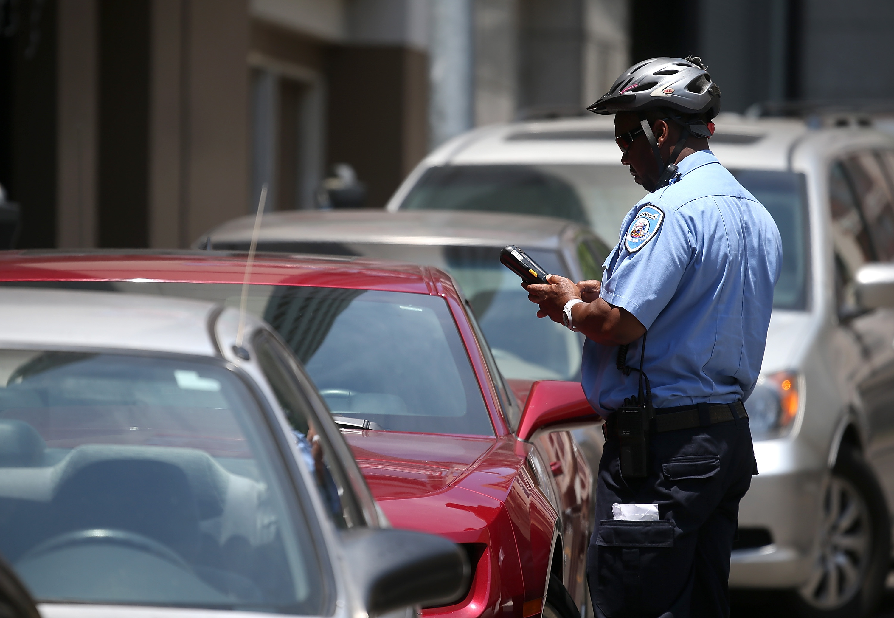 A San Francisco Municipal Transportation Agency parking control officer writes a parking ticket for an illegally parked car on July 3, 2013 in San Francisco.