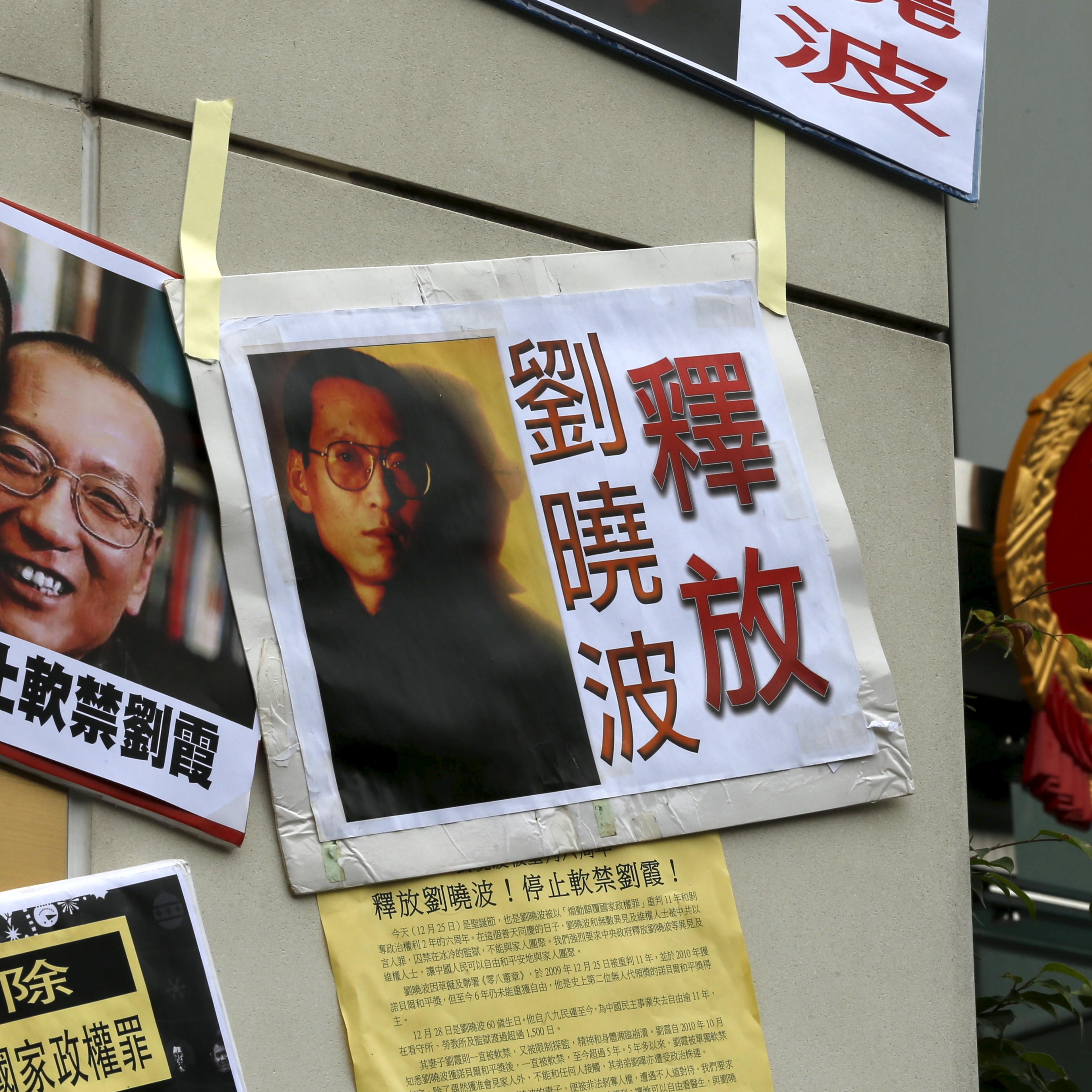 Signs and portraits of jailed Chinese Nobel Peace Prize laureate Liu Xiaobo and his wife Liu Xia are seen in front of the national emblem of China during a protest outside the Chinese liaison office in Hong Kong, China