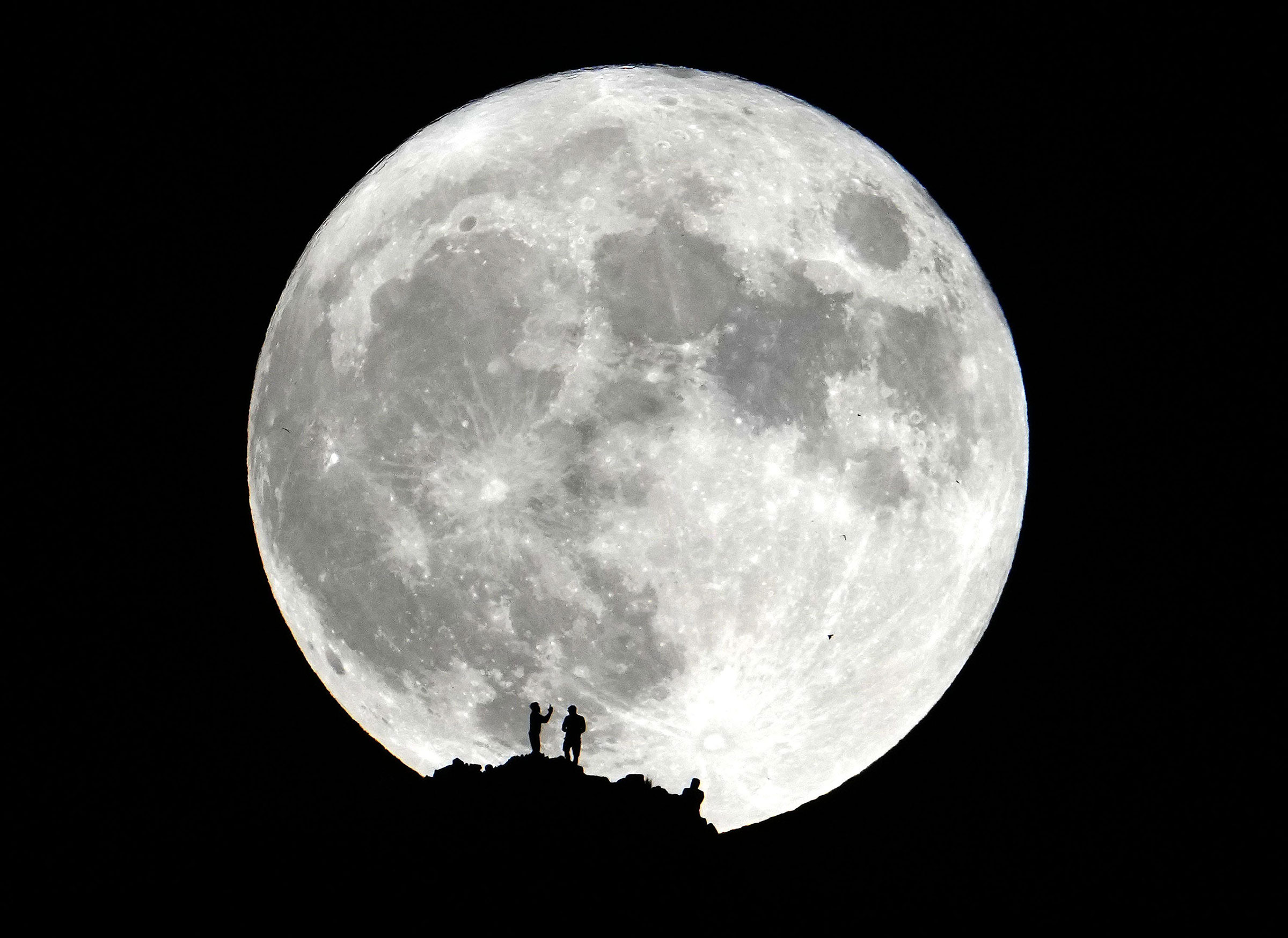 Hikers watch the Super Blue Moon from the summit of Piestewa Peak in Phoenix on Aug. 30, 2023.
