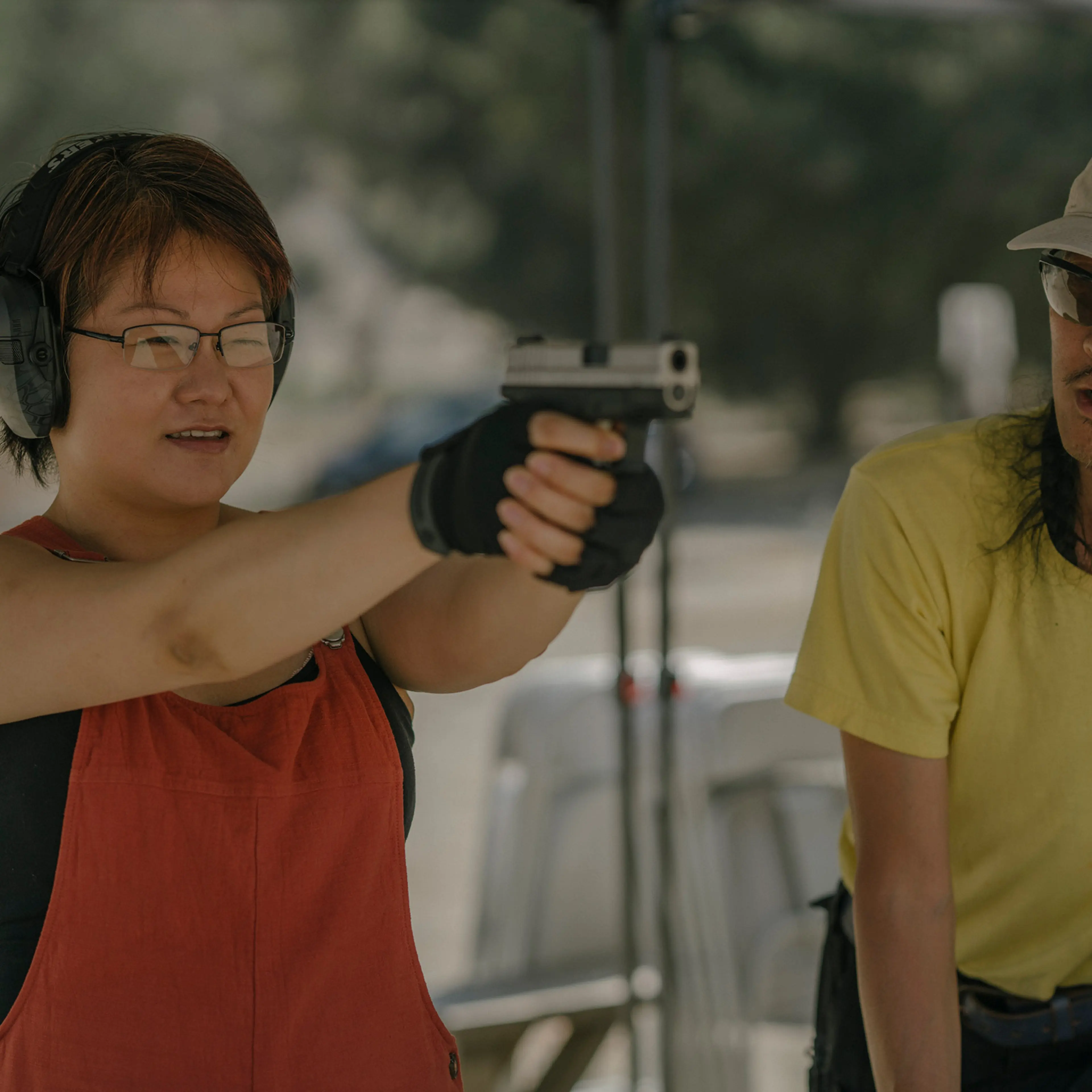 AZUSA, CALIFORNIA - JULY 18, 2021:Svetlana Kim practices shooting her handgun, while standing next to Tom Nguyen, instructor and founder of L.A. Progressive Shooters, at Burro Canyon Shooting Park in Azusa, CA. Svetlana attended beginner’s classes throug
